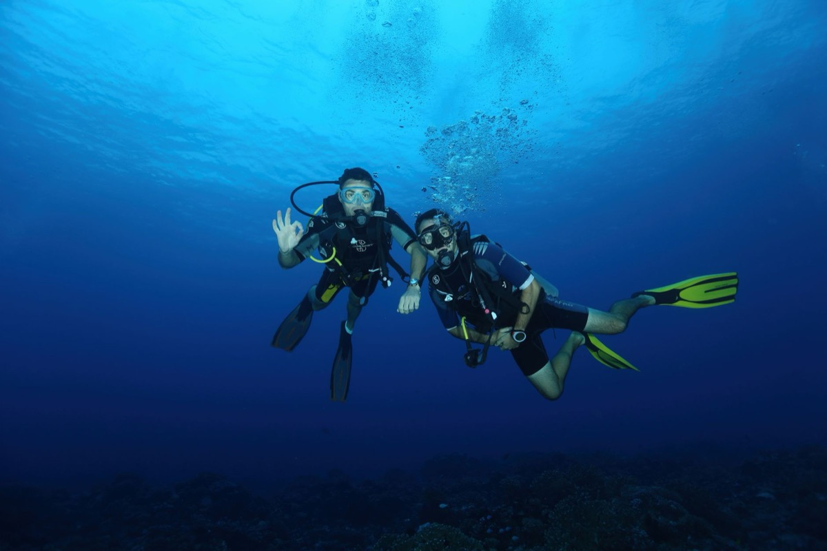 Two scuba divers giving the OK signal underwater off Oman's coast
