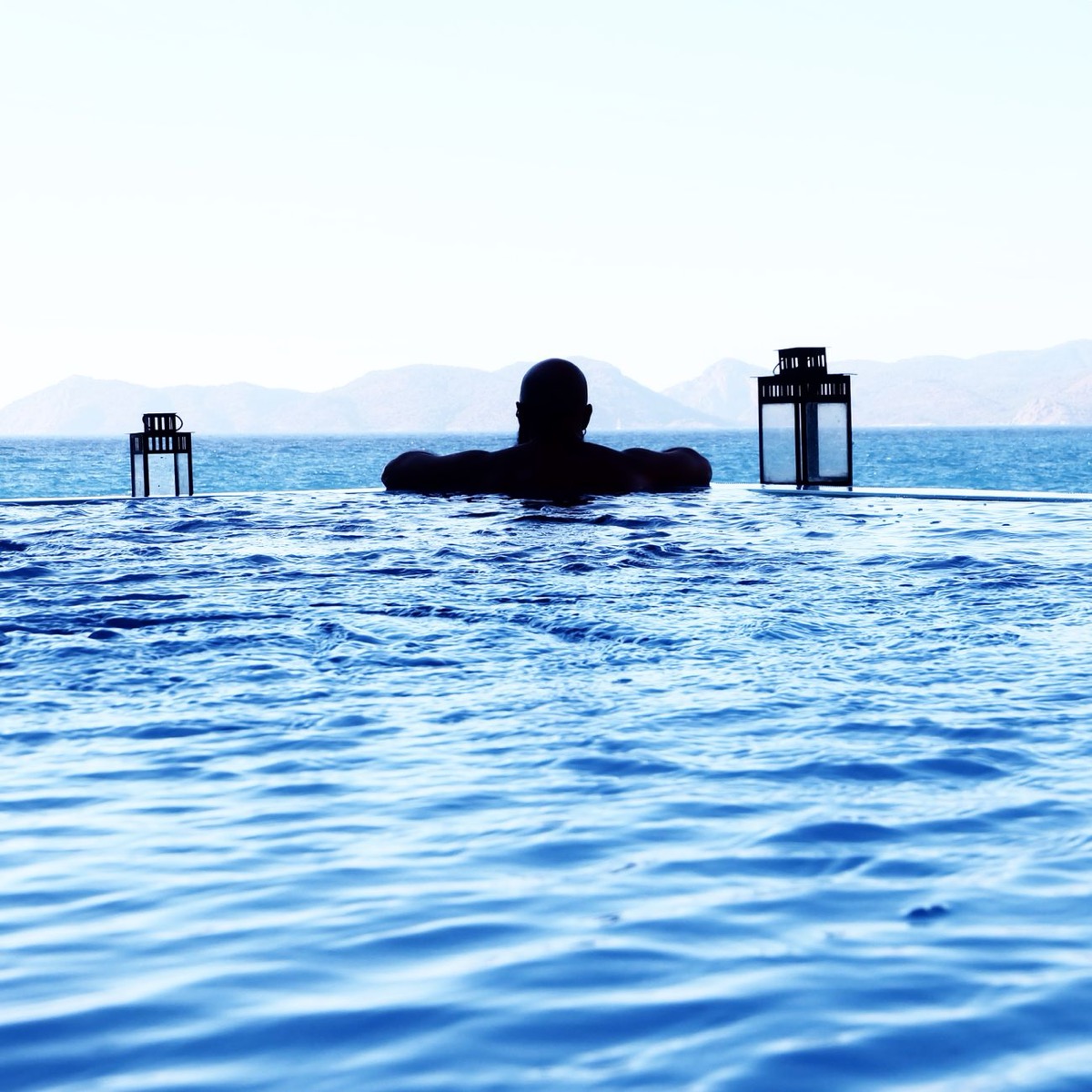 Infinity pool overlooking the sea and mountains at sunset