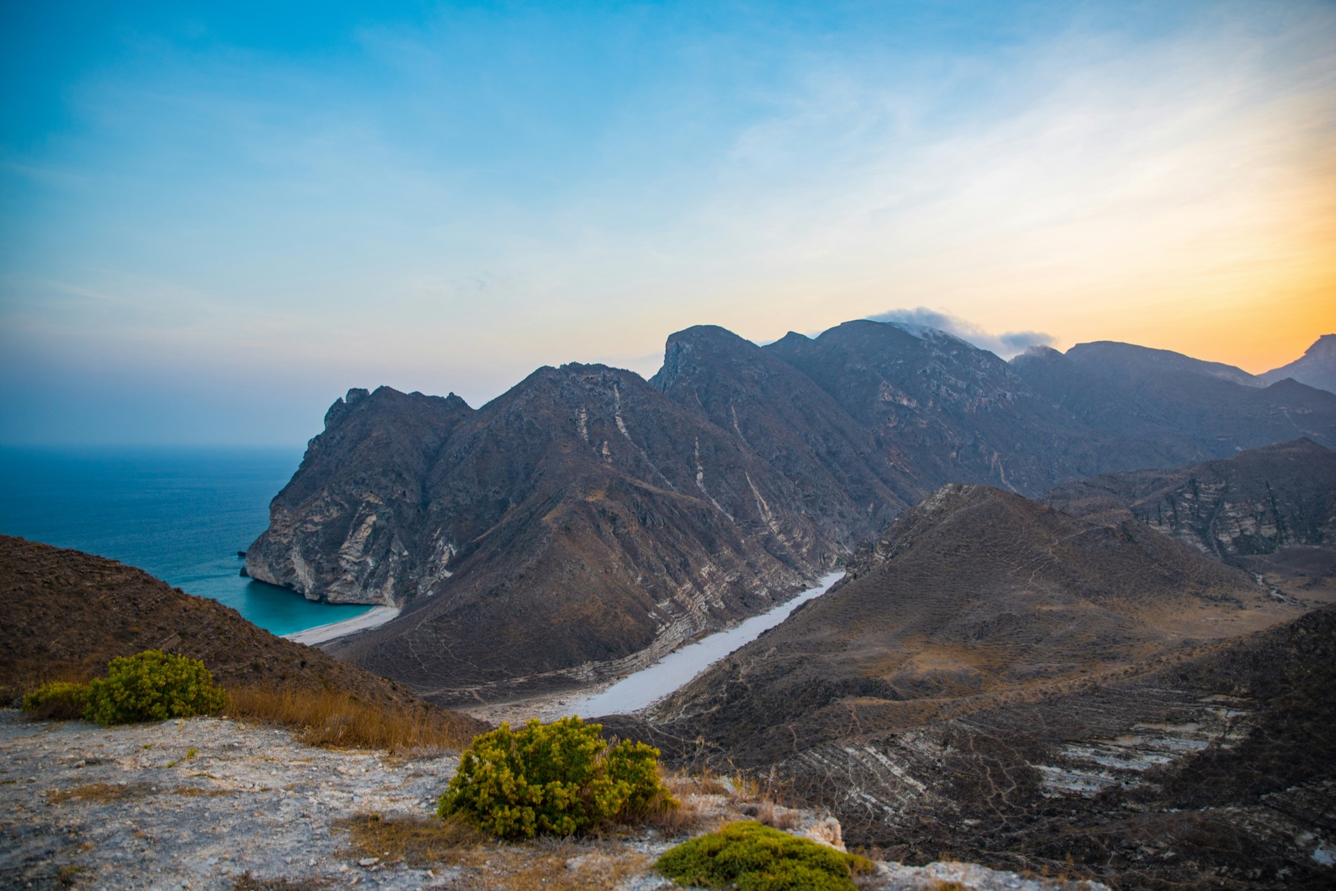 Coastal cliffs and mountains meeting the sea in Oman at sunset